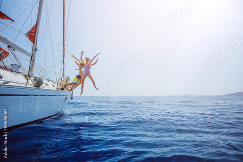 Boy with his sister jump of sailing yacht on summer cruise. Travel adventure, yachting with child © Max Topchii