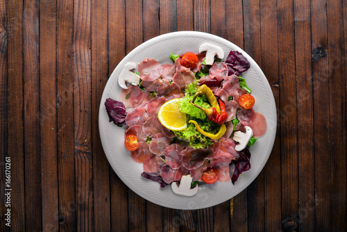 Carpaccio of beef, vegetables, cheese, spices, to Wooden background. Top view. Free space
