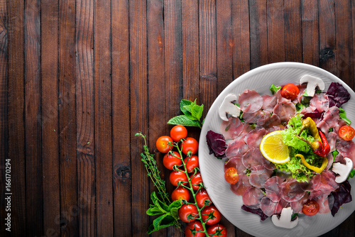 Carpaccio of beef, vegetables, cheese, spices, to Wooden background. Top view. Free space