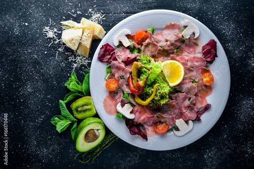 Carpaccio of beef, vegetables, cheese, spices, to Wooden background. Top view. Free space