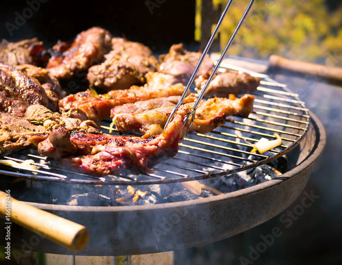 Assorted delicious grilled meat over the coals on a barbecue. Beef, lamb and chicken steaks on the grill with flames. Meat char-grilled over flame.