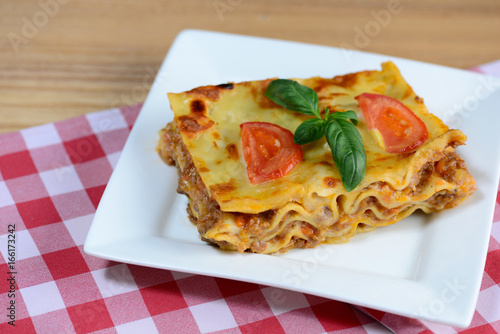 Tasty lasagna served on a wooden table. Italian food background. Closeup.