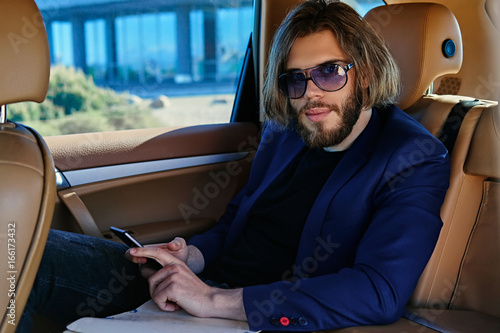 A man in sunglasses using smart phone in a car.