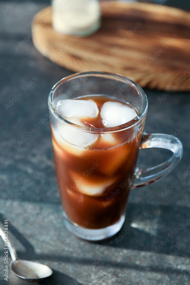 Glass cup with cold brew coffee and spoon on grey table Glass cup with cold brew coffee and spoon on grey table