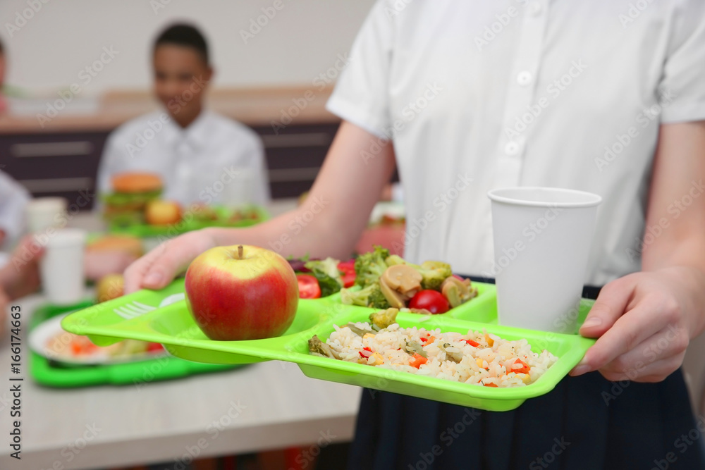 Girl holding tray with delicious food in school canteen, closeup Girl holding tray with delicious food in school canteen, closeup