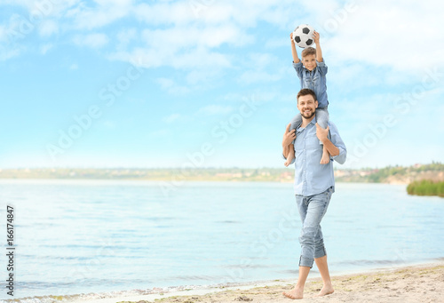 Dad and son with soccer ball on beach