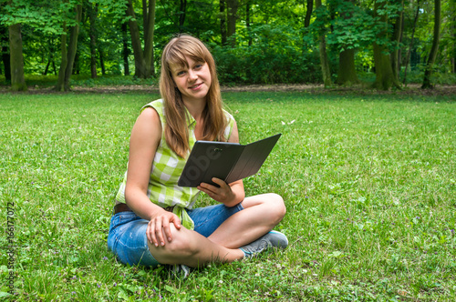 Woman with tablet sitting on grass in park