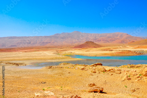 panorama of the central, desert part of Morocco in bright sunny day, on the horizon a small mountain ridge, at her bottom the drying-up lake