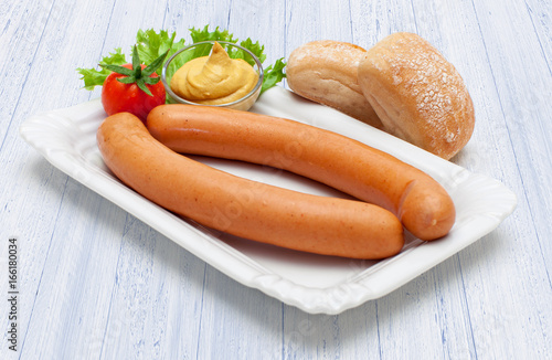 Ein Paar heiße Wiener Würstchen auf Pappdeckel und weißem Holzuntergrund