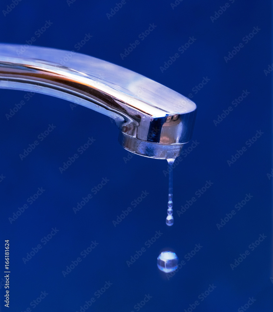 Drops of water dripping from the iron crane on blue background. Concept of rational use of natural resources Drops of water dripping from the iron crane on blue background. Concept of rational use of natural resources