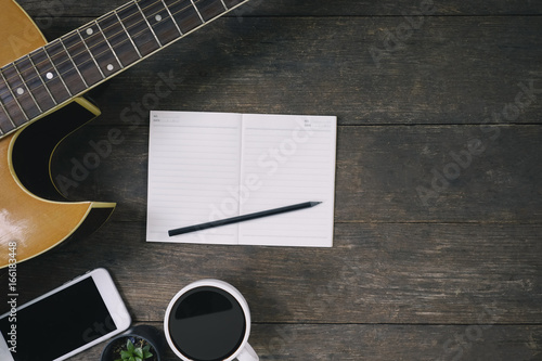 Fotografie Desk of song composer for a work songwriter with a guitar and notepad on wood table