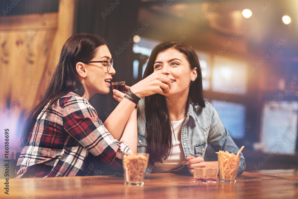 Positive delighted girls drinking tasty liqueur Positive delighted girls drinking tasty liqueur