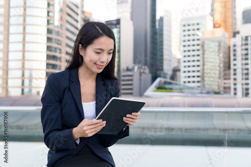 Businesswoman looking on tablet computer at outdoor street