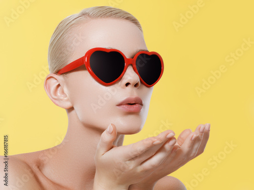love, happiness, valentines day, face expressions and people concept - portrait of teenage girl in pink sunglasses with hearts blowing kiss © looking2thesky