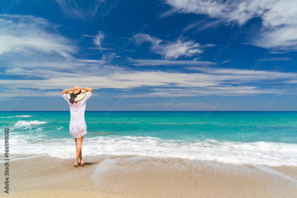 Young woman standing on a beach and enjoying the sun Young woman standing on a beach and enjoying the sun