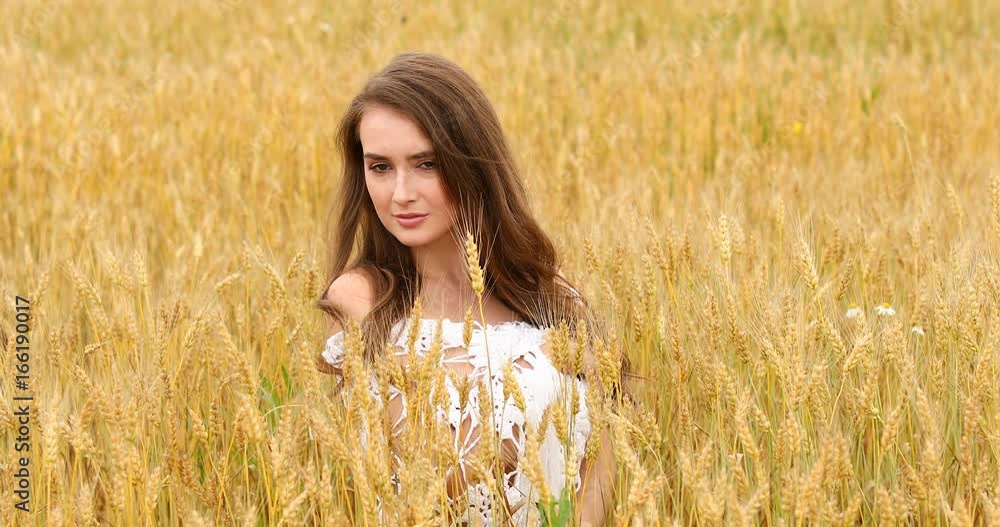 Young beautiful girl posing against a wheat field background Young beautiful girl posing against a wheat field background