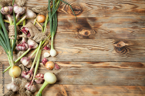 Fresh garlic and onions on rustic wooden background