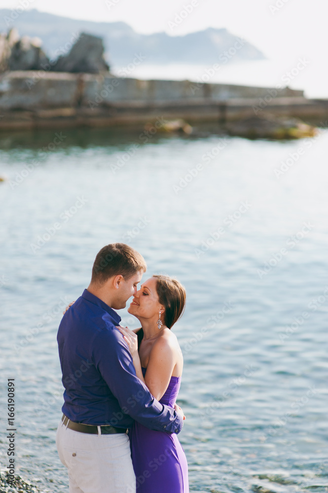A loving couple in purple outfits on the seashore A loving couple in purple outfits on the seashore