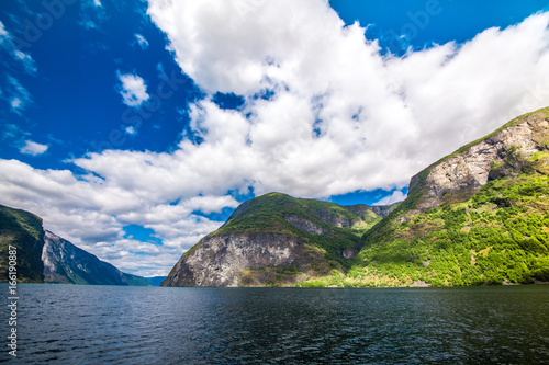 Mountains and fjord in Norway. Clouds and blue sky. Beautiful stunning views of mountains, water, sky, clouds and sun. Norwegian nature