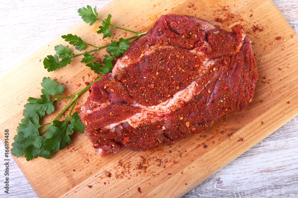 Raw beef steak with spices Leaves of coriander on wooden cutting board. Ready for cooking. Raw beef steak with spices Leaves of coriander on wooden cutting board. Ready for cooking.