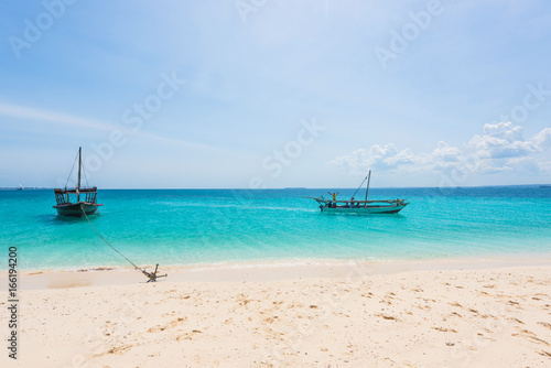 boats near a seashore anchored with blue sky on the background