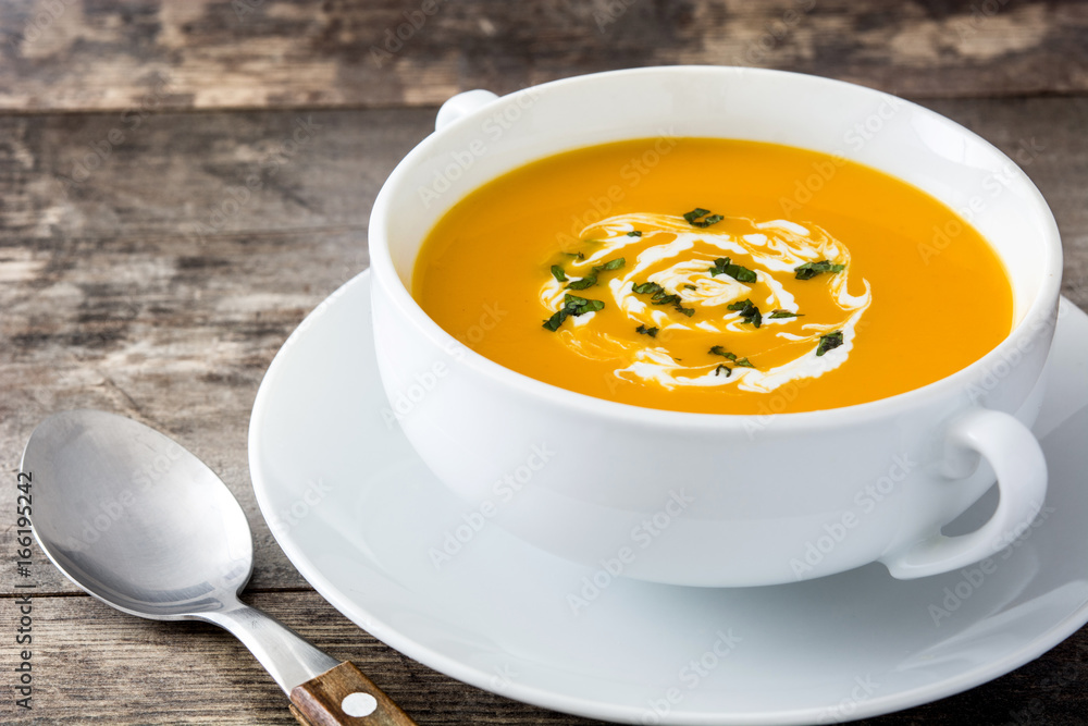 Pumpkin soup in white bowl on wooden table
Pumpkin soup in white bowl on wooden table