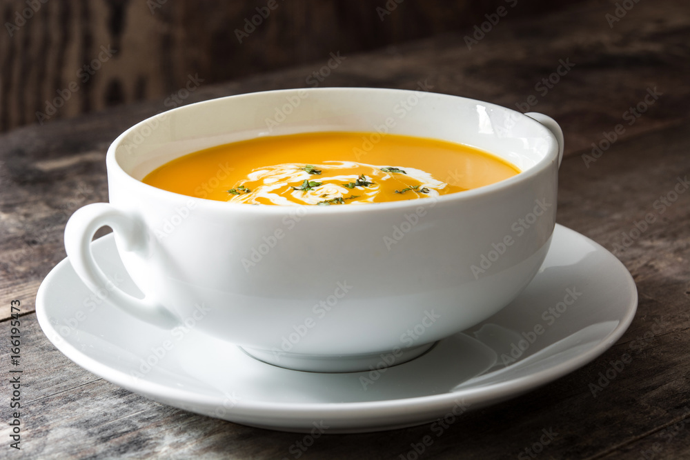 Pumpkin soup in white bowl on wooden table
Pumpkin soup in white bowl on wooden table