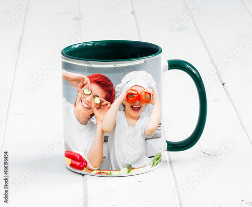 Big green cup with dark green handle and print of a kids cooking something photo