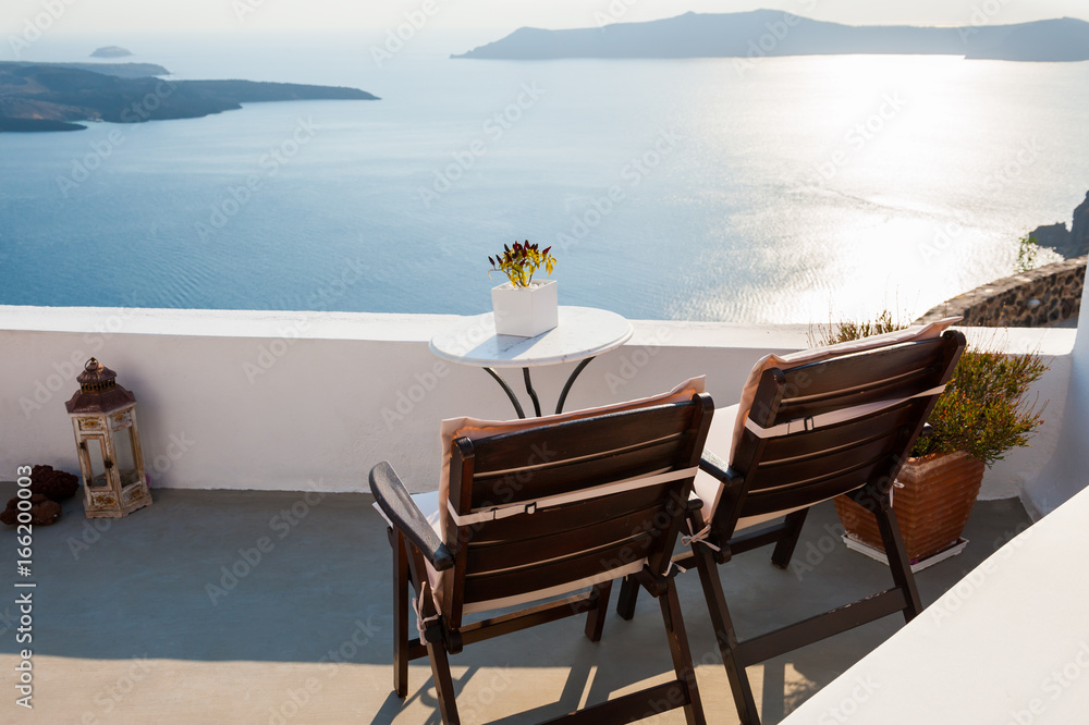Two chairs on the terrace, sea view. Santorini island, Greece. Travel and vacation