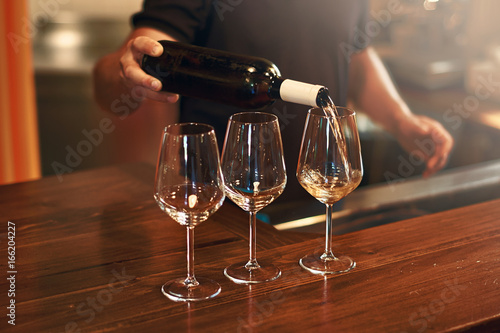 Sommelier pours pinot gris wine in glasses for degustation photo