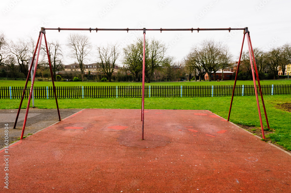 Swing frame with missing swings in an inner city childrens play park. Swing frame with missing swings in an inner city childrens play park.