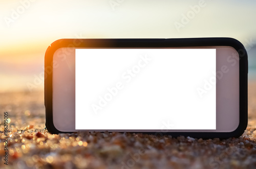Smart phone on sand beach texture background.