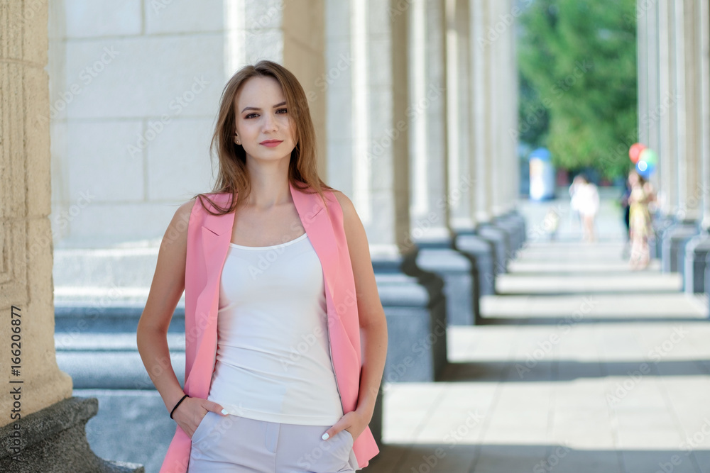 Outdoor portrait of beautiful young woman near column