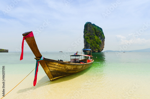 Boat anchored near a tropical beach in Krabi with rock formation in the background, Thailand © Em Campos