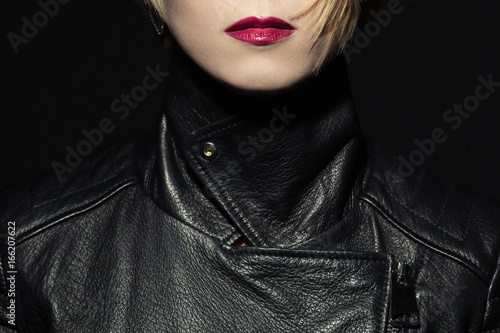 Tough girl and femme fatale concept. Rock star style. Close up portrait of young woman wearing expensive luxurious black leather jacket. Studio shot