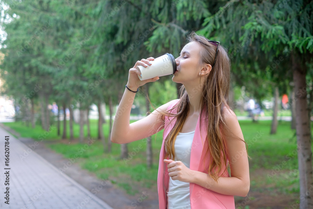 Beautiful happy young woman drinking coffee in park Beautiful happy young woman drinking coffee in park
