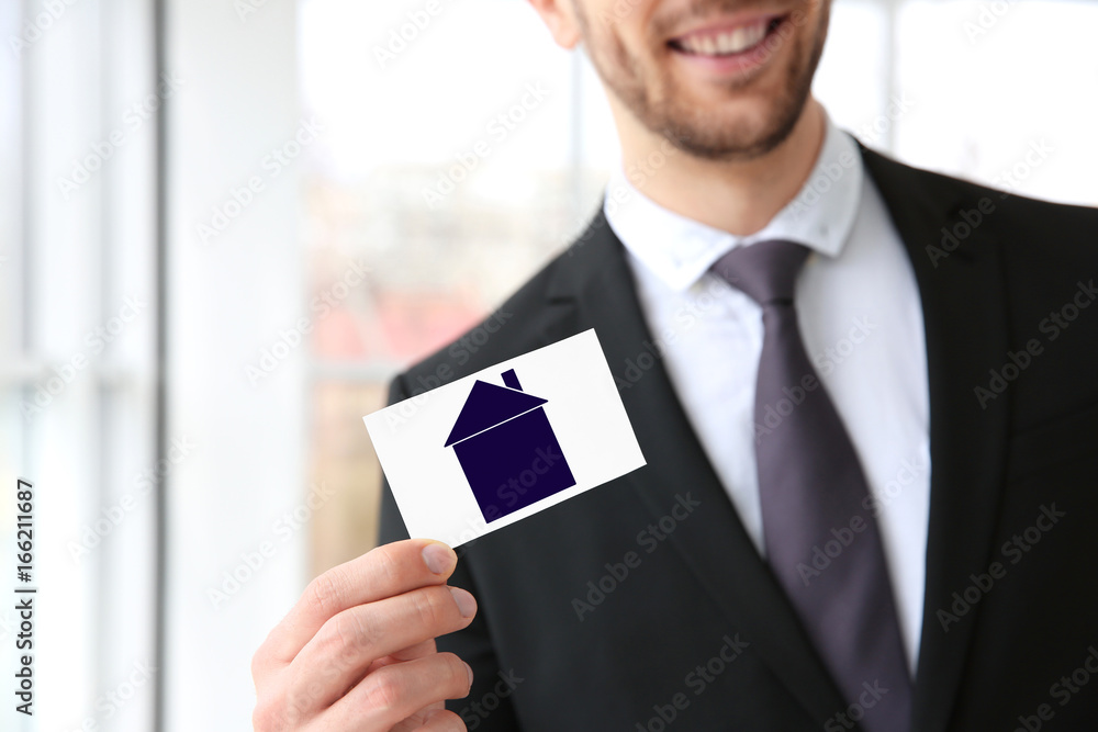Handsome young man with business card on blurred background, closeup Handsome young man with business card on blurred background, closeup