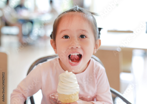 Cute little child girl eating ice cream.