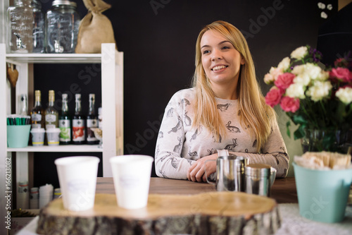 Young woman barista working in coffee shop. Smiling girl at the bar in the cafe