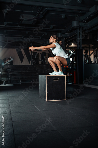 Young woman doing a box jump exercise. © takoburito
