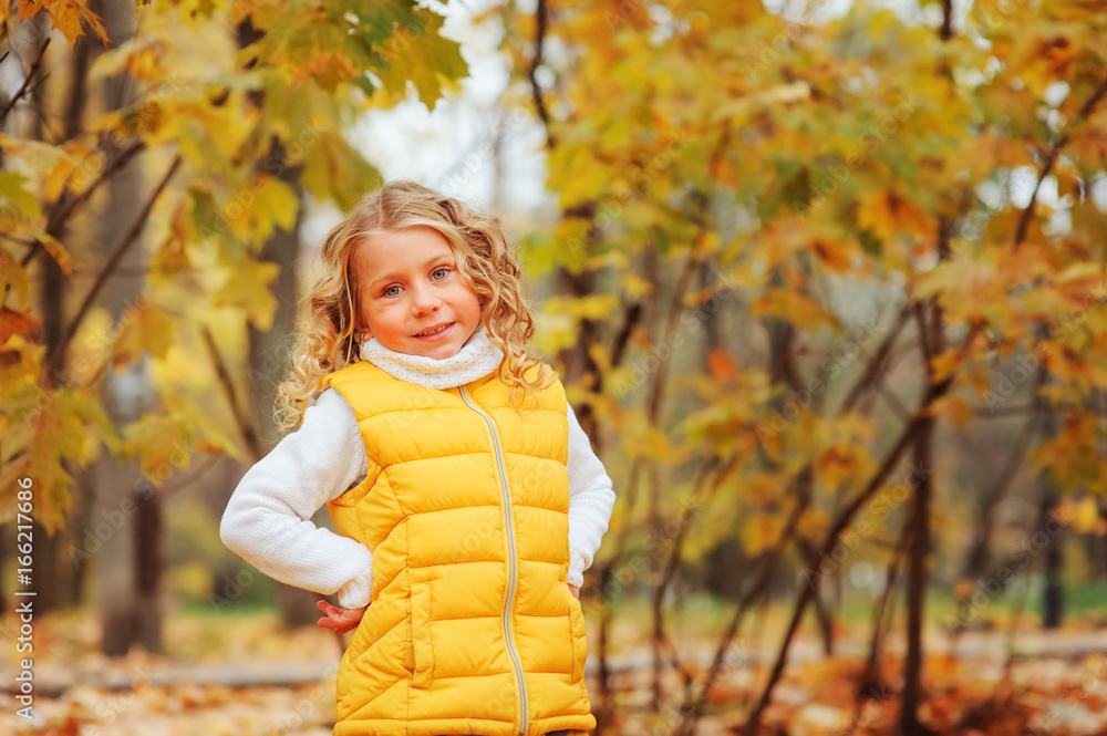cute toddler girl playing with leaves in autumn park on the walk, wearing fashion yellow outfit cute toddler girl playing with leaves in autumn park on the walk, wearing fashion yellow outfit