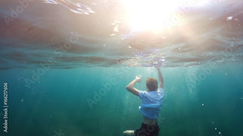 young man sinking into the sea