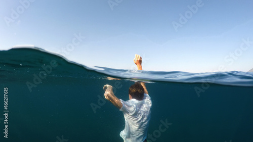Fotografie, Obraz young man sinking into the sea
