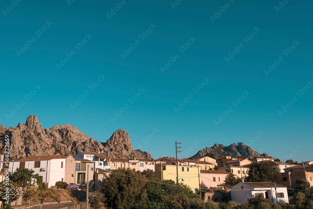 Colorful houses in evening sunlight against mountain landscape. Sardinia. Italy.