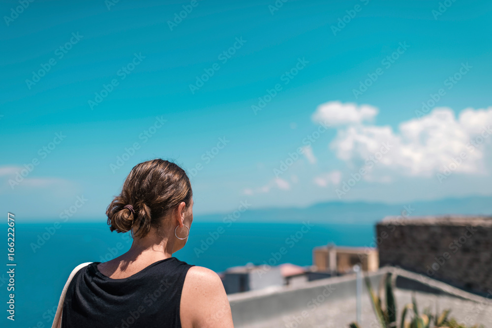 Brunette woman enjoying ocean view from roof top. Sardinia. Italy.