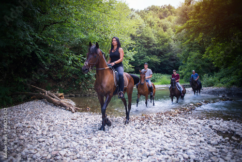 Group of friends riding horses on the river