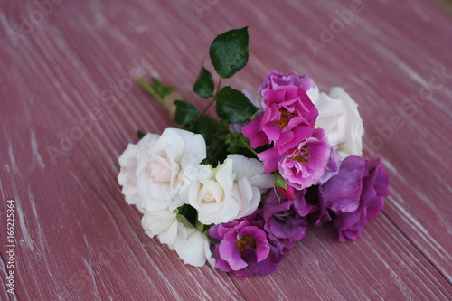 Bouquet of pink and purple garden roses on a wooden background