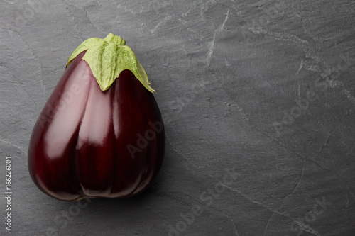 Fresh ripe bell shaped eggplant on dark stone background, top view
