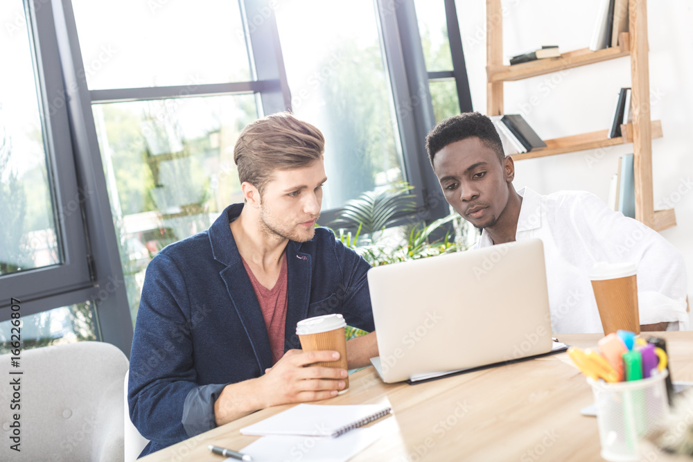 portrait of multicultural focused businessmen working on laptop at workplace portrait of multicultural focused businessmen working on laptop at workplace
