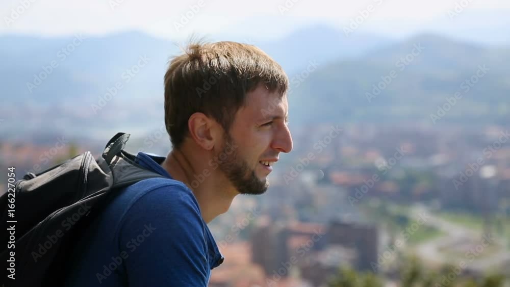 Male tourist looking over big city, covering eyes with hand against sun, travel Male tourist looking over big city, covering eyes with hand against sun, travel